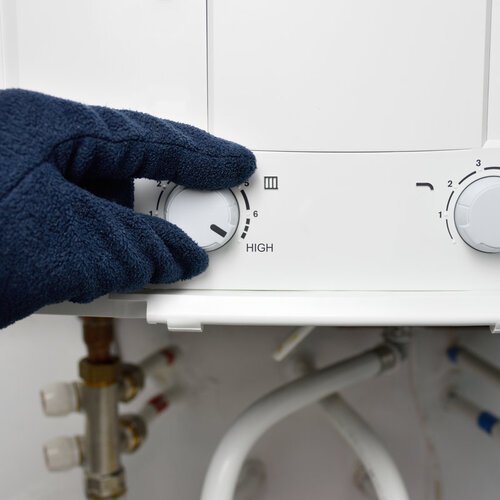 worker adjusting the dials on a tankless water heater