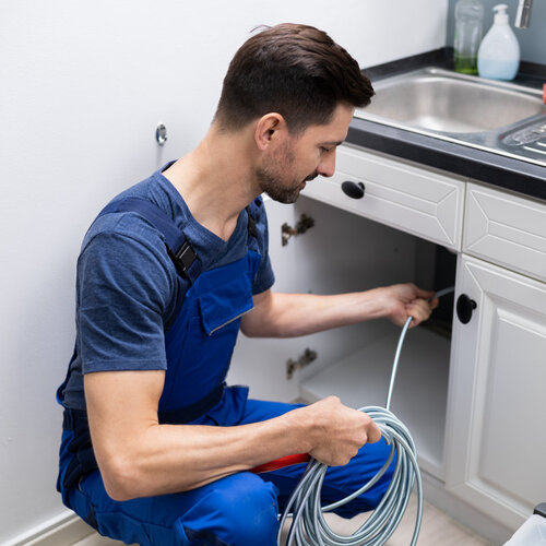 plumber providing drain cleaning for a kitchen sink