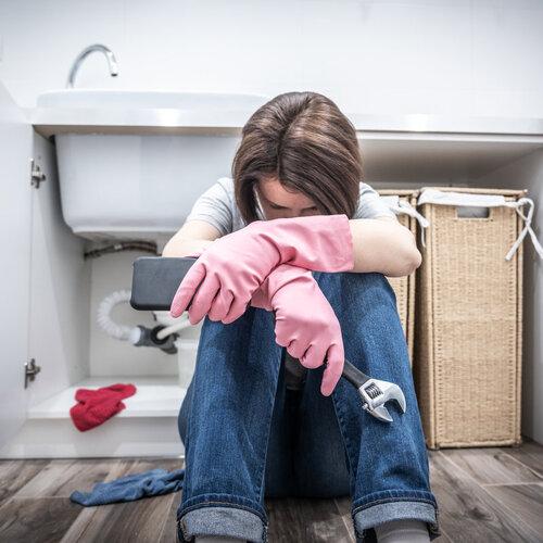 upset woman preparing to call an emergency plumber