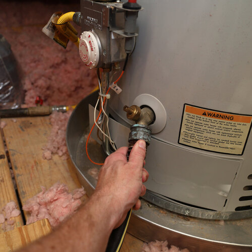 close-up of a technician attaching a hose to a home water heater