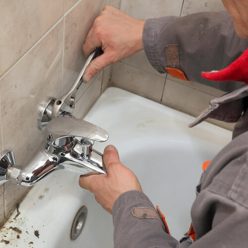 close-up of a plumber repairing a bathtub faucet