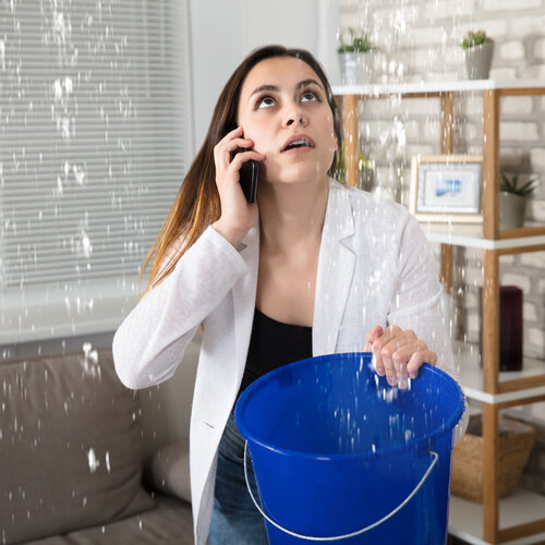 woman dealing with a leak and calling an emergency plumber