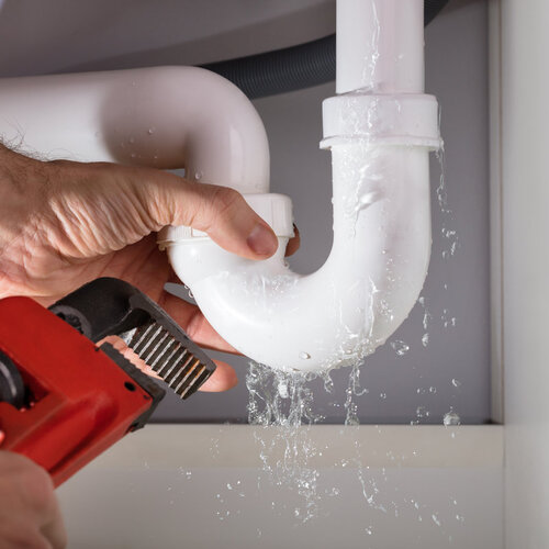 close-up of a plumber fixing a leaking pipe